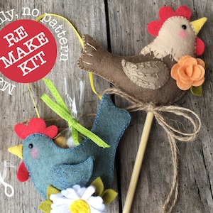 May include: A felt craft kit to make two felt chickens. One chicken is brown with an orange flower and the other is blue with a white daisy. The kit includes all materials needed, except for scissors. The kit is labeled "RE MAKE KIT, materials only, no pattern".