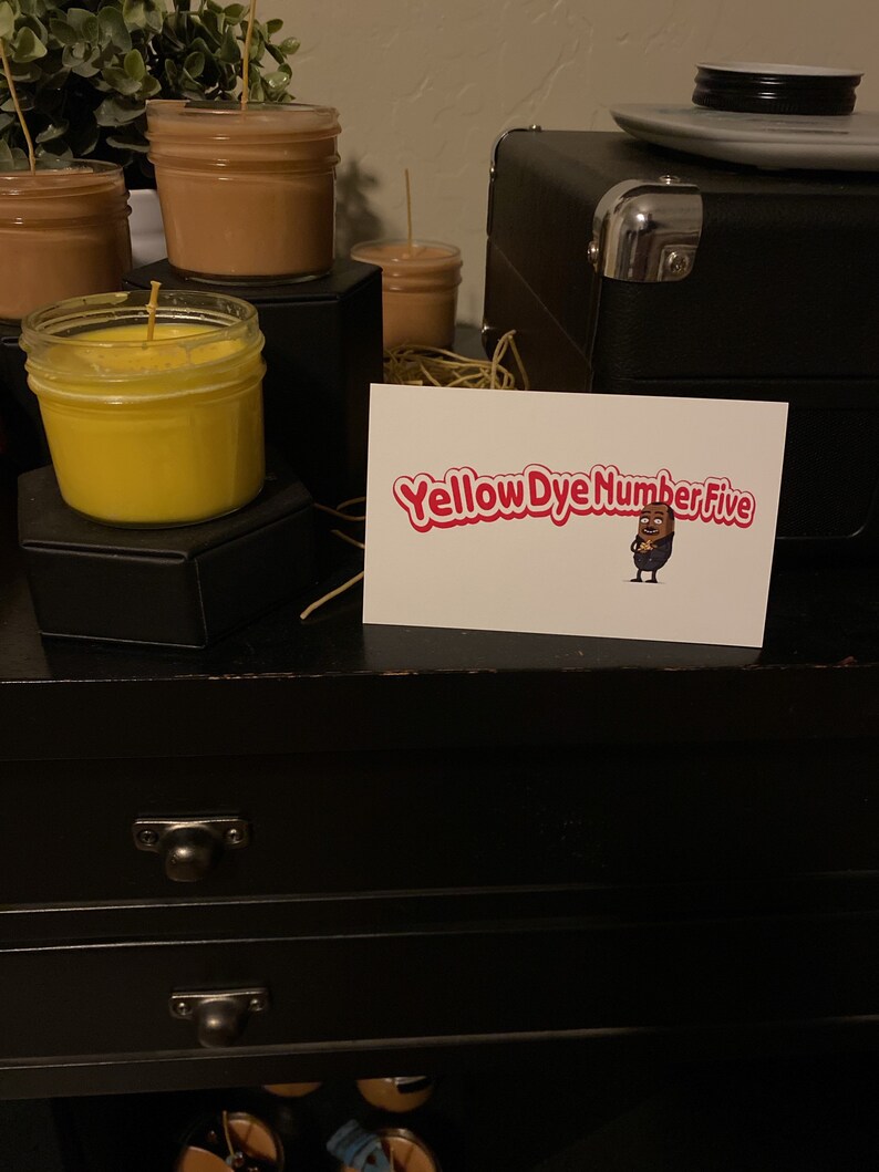 May include: A black wooden dresser with two drawers and a card on top that says "Yellow Dye Number Five" with a cartoon character holding a jar of yellow dye.