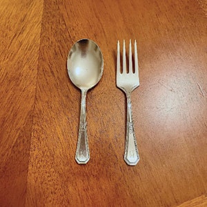 Può includere: Un set di posate per bambini in argento, composto da un cucchiaio e una forchetta, su una superficie di legno.