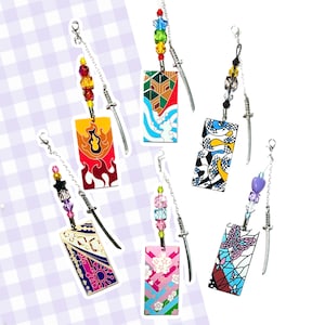 May include: Six colourful charms with different patterns and designs. Each charm is attached to a silver chain with beads and a small silver sword. The charms are rectangular and feature various patterns, including flames, flowers, and geometric shapes.