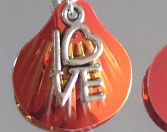 Silver love charms with shimmering reds & golds behind. Enjoy the love energy or gift to someone in need - spread your love charm with joy