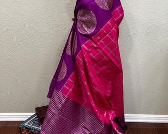 Puede incluir: Un sari de seda morado y rosa con un diseño bordado en oro. El sari tiene un patrón a cuadros y un borde con un diseño floral.