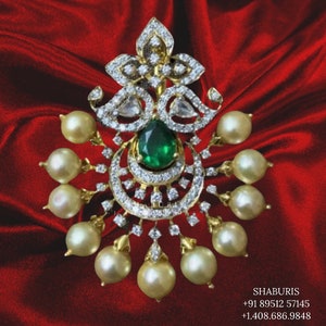 May include: A gold pendant with a green gemstone and white diamonds, surrounded by a cluster of pearls.