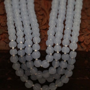 May include: A multi-strand necklace made of light blue beads. The beads are round and have a slightly textured surface.