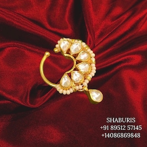 May include: A gold nose ring with a teardrop-shaped pendant and a row of small white pearls. The ring is decorated with clear gemstones.