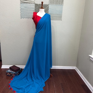 May include: A turquoise blue saree with red and white tassels. The saree is draped on a mannequin and has a red blouse.