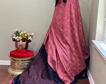 Puede incluir: Un sari rosa y negro con estampado, con una blusa negra. El sari tiene un patrón geométrico y está drapeado sobre un maniquí.