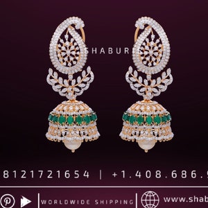 May include: A pair of gold earrings with a teardrop-shaped design, featuring a cluster of white stones and a green stone accent. The earrings are adorned with a pearl at the bottom.
