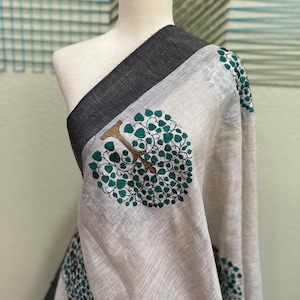 May include: A white linen scarf with a black border and a green and gold tree design.