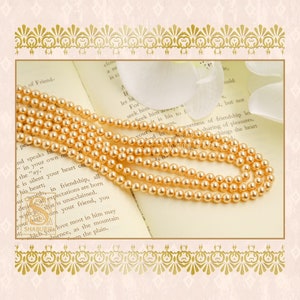 May include: A strand of golden pearl beads on a book with text about friendship. The pearls are round and smooth, and the book is open to a page with text about friendship.