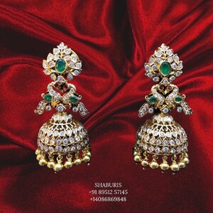 May include: A pair of gold earrings with white stones and green and red accents. The earrings are in the shape of a bell with a decorative top.