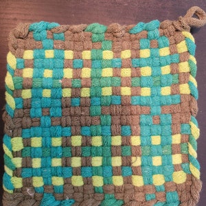 Könnte beinhalten: Ein gewebter Topflappen mit einem karierten Muster in Braun, Grün und Gelb.