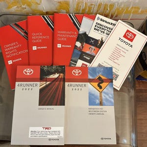 May include: A set of owner's manuals for a 2022 Toyota 4Runner. The manuals include a quick reference guide, warranty and maintenance guide, owner's manual, and navigation and multimedia system owner's manual. The manuals are all in red and grey with the Toyota logo.