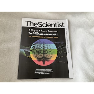 Puede incluir: Una copia de la revista "The Scientist". La portada presenta el título "The Scientist" en texto blanco y negro. El artículo de portada es "From Soundwaves to Brainwaves: The Transformative Power of Music". Un gráfico de un cerebro está en el centro.
