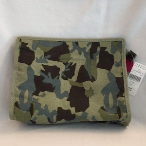Può includere: Una pochette con cerniera a stampa mimetica verde, marrone e blu con un'etichetta nera e rosa che recita "Barneys New York".