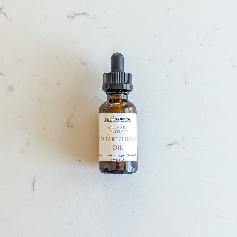May include: A brown glass bottle with a dropper top containing organic unrefined sea buckthorn oil. The bottle is labeled "The Potter's Mixtress" and lists the oil as unrefined, vegan, and chemical-free. The bottle contains 30 ml or 1 oz of oil.