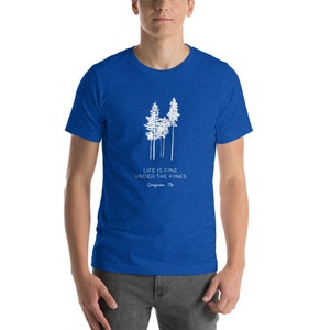 May include: A royal blue t-shirt featuring a white graphic of pine trees and the text "Life is fine under the pines" with the words "Dongusuu, Tx" underneath.