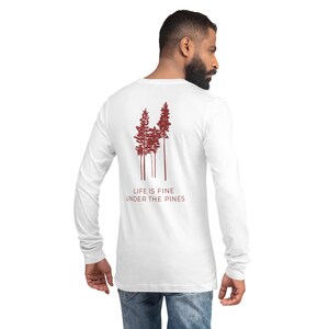 May include: White long-sleeved shirt with a red silhouette of pine trees and the text "Life is fine under the pines".