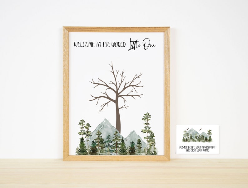 Pu&ograve; includere: Una stampa incorniciata con un'illustrazione ad acquerello di un albero con montagne e pini sullo sfondo. Il testo "Welcome to the world Little One" &egrave; in cima alla stampa. Un biglietto pi&ugrave; piccolo con il testo "Please leave your fingerprint and sign your name" &egrave; nell'angolo in basso a destra dell'immagine.