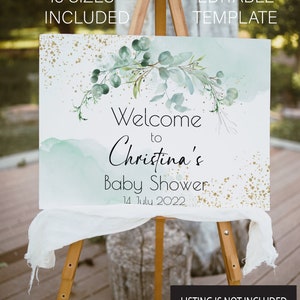 May include: A welcome sign for a baby shower with a watercolor background in shades of blue and green. The sign features a leafy garland with gold glitter accents and the text "Welcome to Christina's Baby Shower 14 July 2022".