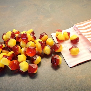 May include: A pile of red and yellow dice with a striped fabric pouch in the background.