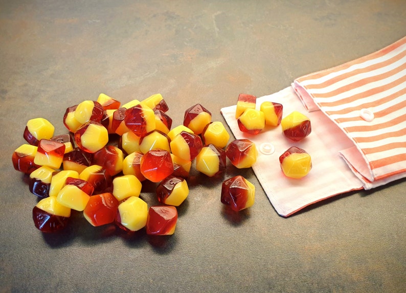 May include: A pile of red and yellow dice with a striped fabric pouch in the background.