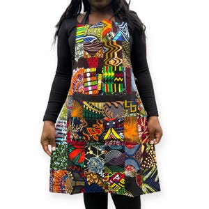 Può includere: Grembiule patchwork colorato con un'ampia tasca frontale. Il grembiule presenta una varietà di vivaci motivi in tessuto africano in rosso, giallo, blu e verde. Progettato per l'uso in cucina o artigianato.