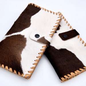 Puede incluir: Dos carteras de piel de vaca marr&oacute;n y blanca con costuras de color canela y cierres a presi&oacute;n negros.