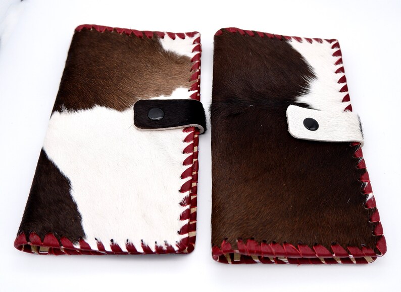 Puede incluir: Dos carteras de piel de vaca marr&oacute;n y blanca con costuras rojas y cierre de correa de cuero negro.
