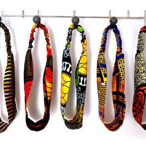 Op de afbeelding: Vijf kleurrijke haarbanden met Afrikaanse printstof. De haarbanden zijn gemaakt van elastisch materiaal en zijn ontworpen om om het hoofd te worden gedragen.
