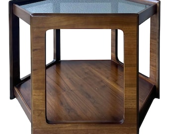 May include: A hexagonal shaped wooden coffee table with a glass top and a lower shelf. The table is made of dark wood and has a modern design.