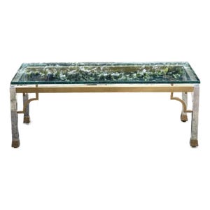 May include: A rectangular coffee table with a glass top and a decorative interior filled with greenery. The table has a gold-colored frame and silver-colored legs. The table is approximately 48 inches long and 24 inches wide.