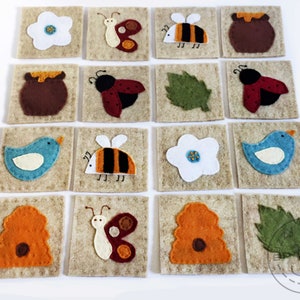 May include: A collection of sixteen felt squares, each featuring a different nature-themed design. The designs include a white flower, a butterfly, a bee, a honey pot, a ladybug, a green leaf, and a blue bird. The squares are beige with stitched edges.
