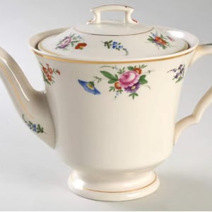 Peut inclure: Une théière en céramique blanche avec un motif floral. La théière a un couvercle et une poignée. Les fleurs sont dans des tons de rose, bleu, jaune et orange.