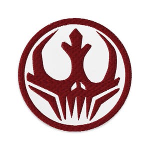 Può includere: Toppa ricamata circolare con un design bordeaux e bianco. La toppa ha un bordo bordeaux. Il design centrale è un emblema stilizzato in bordeaux, su sfondo bianco. L'emblema ha l'aspetto di un teschio.