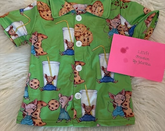 May include: A green short-sleeved button-down shirt with a pattern of mice holding cookies and glasses of milk. The shirt has a white collar and buttons. The text "LEVH Creation By Martha" is written on a pink note card.