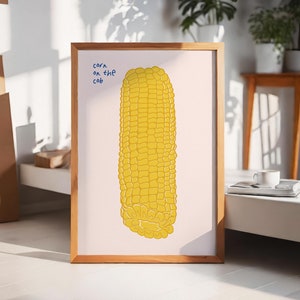 May include: A framed illustration of a yellow corn on the cob with the text "corn on the cob" written in blue.