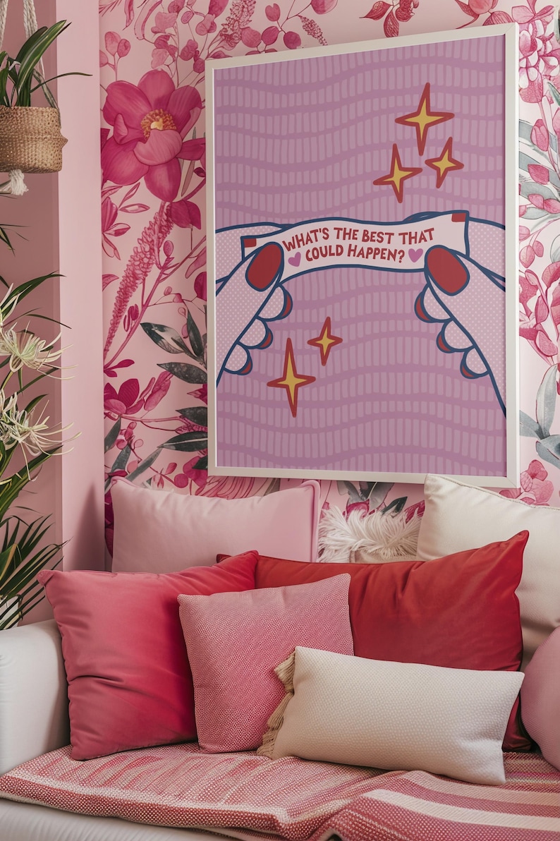 Peut inclure: Une affiche encadr&eacute;e avec le texte "WHAT'S THE BEST THAT COULD HAPPEN?" est affich&eacute;e sur un mur tapiss&eacute; de papier peint floral rose. L'affiche pr&eacute;sente des mains tenant une banni&egrave;re avec le texte et des illustrations d'&eacute;toiles. Plusieurs coussins roses et rouges sont dispos&eacute;s sur un canap&eacute; blanc.