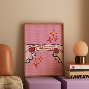 Peut inclure: Une affiche encadr&eacute;e avec un fond rose et le texte "WHAT'S THE BEST THAT COULD HAPPEN?" tenu par des mains illustr&eacute;es. L'affiche pr&eacute;sente des &eacute;clats d'&eacute;toiles rouges et dor&eacute;s et est expos&eacute;e sur une surface violette.