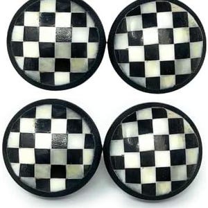 May include: Four round decorative objects with a black and white checkered pattern. Each object has a black border and a glossy finish. The objects are arranged in a square formation against a white background.
