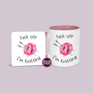 11oz ceramic mug in white with pink accents and an optional white MDF matching coaster. It has the words “Fuck off I’m knitting” with an illustration of a pink ball of yarn with knitting needles. mug is microwave & dishwasher safe.