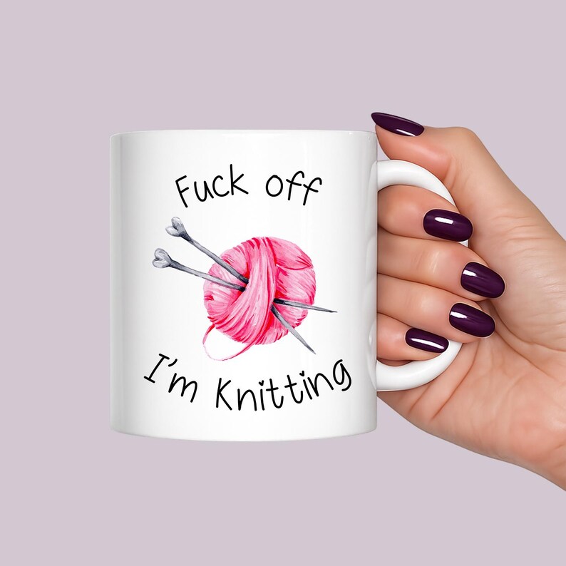 Funny knitting mug featuring pink yarn ball and knitting needles with humorous quote saying Fuck Off I’m Knitting.