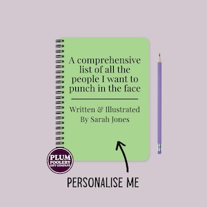 May include: A green spiral bound notebook with the text "A comprehensive list of all the people I want to punch in the face" and "Written & Illustrated By Sarah Jones". A purple pencil is to the right of the notebook. A sticker with the text "Plum Foolery Gift Company" is on the bottom left corner of the notebook.