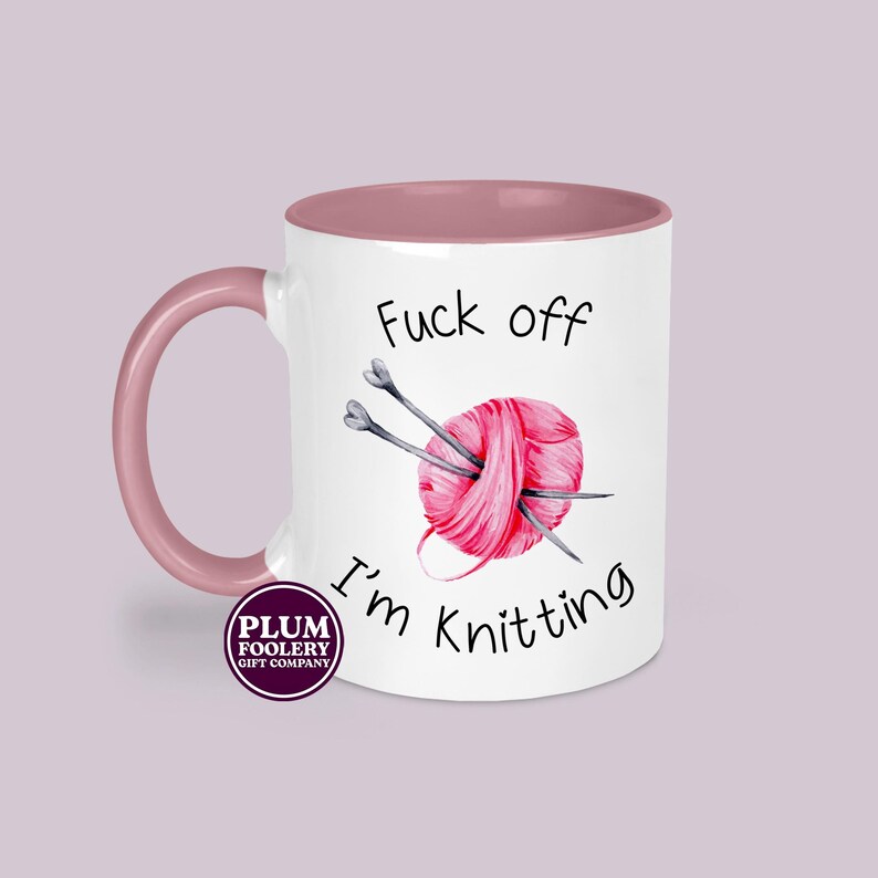 11oz ceramic mug in white with pink accents, mug only. It has the words “Fuck off I’m knitting” with an illustration of a pink ball of yarn with knitting needles. mug is microwave & dishwasher safe.