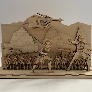 May include: A wooden model of a Star Wars scene featuring Ahsoka Tano and a clone trooper facing off. The scene includes a clone army, a Republic gunship, and a building with the symbol of the Republic.