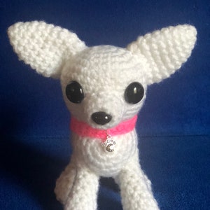May include: White crocheted chihuahua dog toy with black eyes and a pink collar with a silver paw charm.