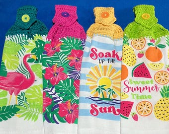 May include: Four decorative kitchen towels with crochet tops. The towels feature tropical designs, including a flamingo, hibiscus flowers, and the text "Soak Up The Sun" and "Sweet Summer Time". Each towel has a different color scheme.