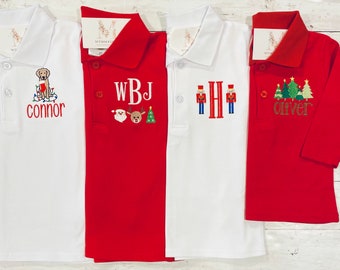 May include: Four long-sleeved polo shirts in white and red. Each shirt features embroidered designs: a dog with lights and the name "connor", initials "WBJ" with Santa, a reindeer, and a tree, initials "H" with nutcrackers, and Christmas trees with the name "oliver".