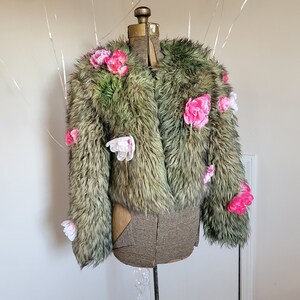 May include: A green faux fur jacket with pink and white flower embellishments.