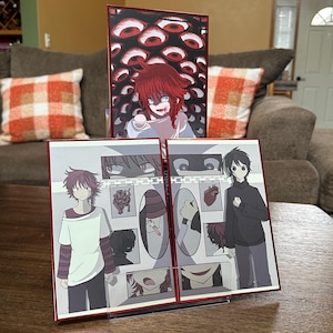 以下が含まれることがあります： 3つのアニメスタイルのアートプリントのセット。中央のプリントは、背景に多くの目を持つ赤毛のキャラクターが特徴です。他の2つのプリントは、暗い色のパレットでキャラクターとイラストを備えた漫画スタイルのパネルを示しています。